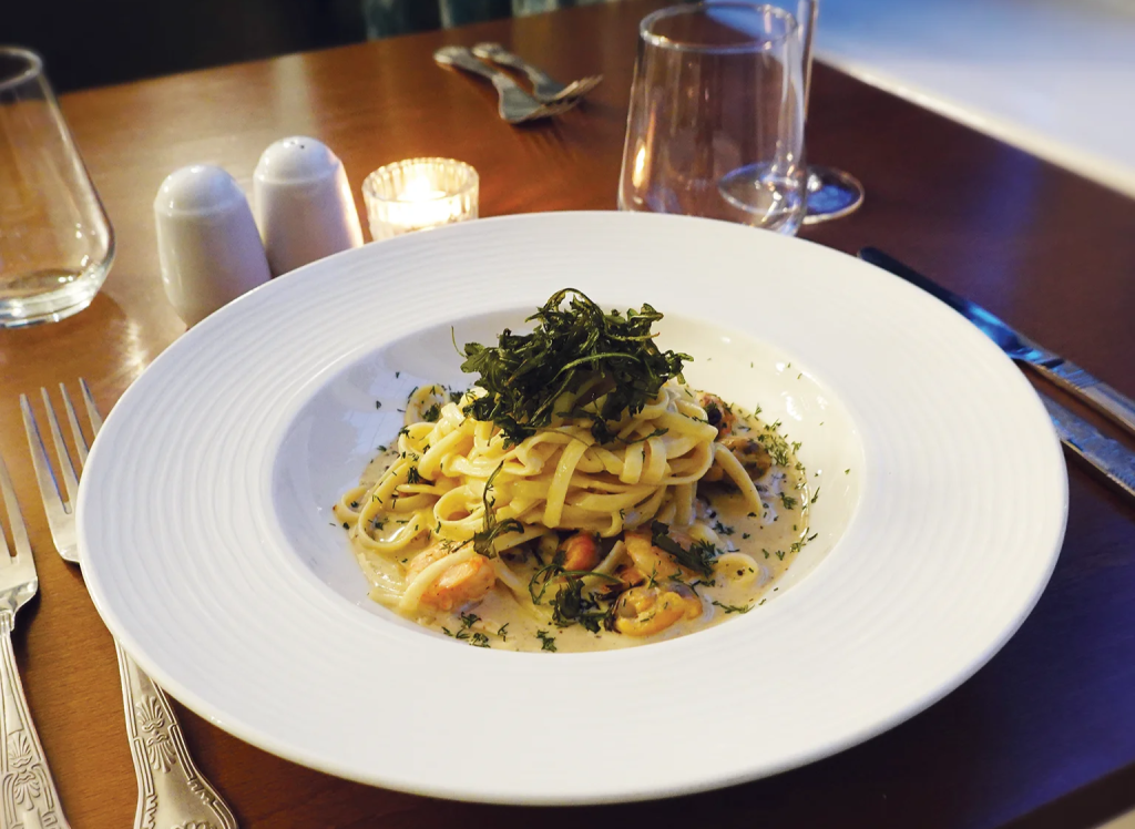 Image of a seafood pasta dish on a table in Broome Park Hotel's Peacock Restaurant